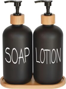 Black glass bathroom soap dispenser set with bamboo pumps and matching tray on a modern bathroom countertop.