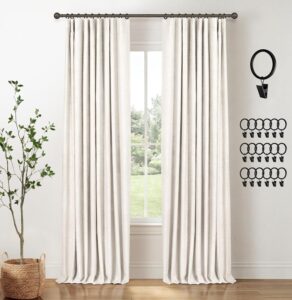 Beige linen-look 100% blackout curtains hanging in a bright modern living room with black curtain rings.