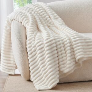 Cream striped fleece throw blanket draped over a modern beige sofa, ultra-soft decorative throw for living room, bedroom, and cozy home décor.