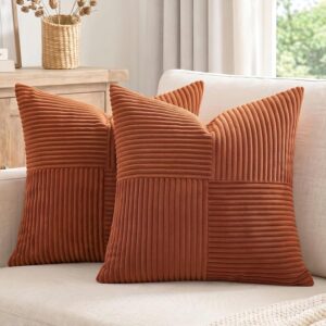 Set of two rust-colored corduroy decorative throw pillow covers on a cream living room sofa.