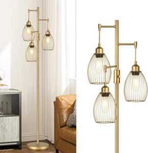 Gold industrial tree floor lamp with three teardrop-shaped cage shades beside a modern leather sofa in a stylish living room