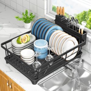 Compact black dish drying rack with plate holder, utensil organizer, and drip tray on a modern kitchen countertop beside the sink.