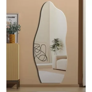 Modern frameless asymmetrical wall mirror hanging in a contemporary living room with neutral décor.